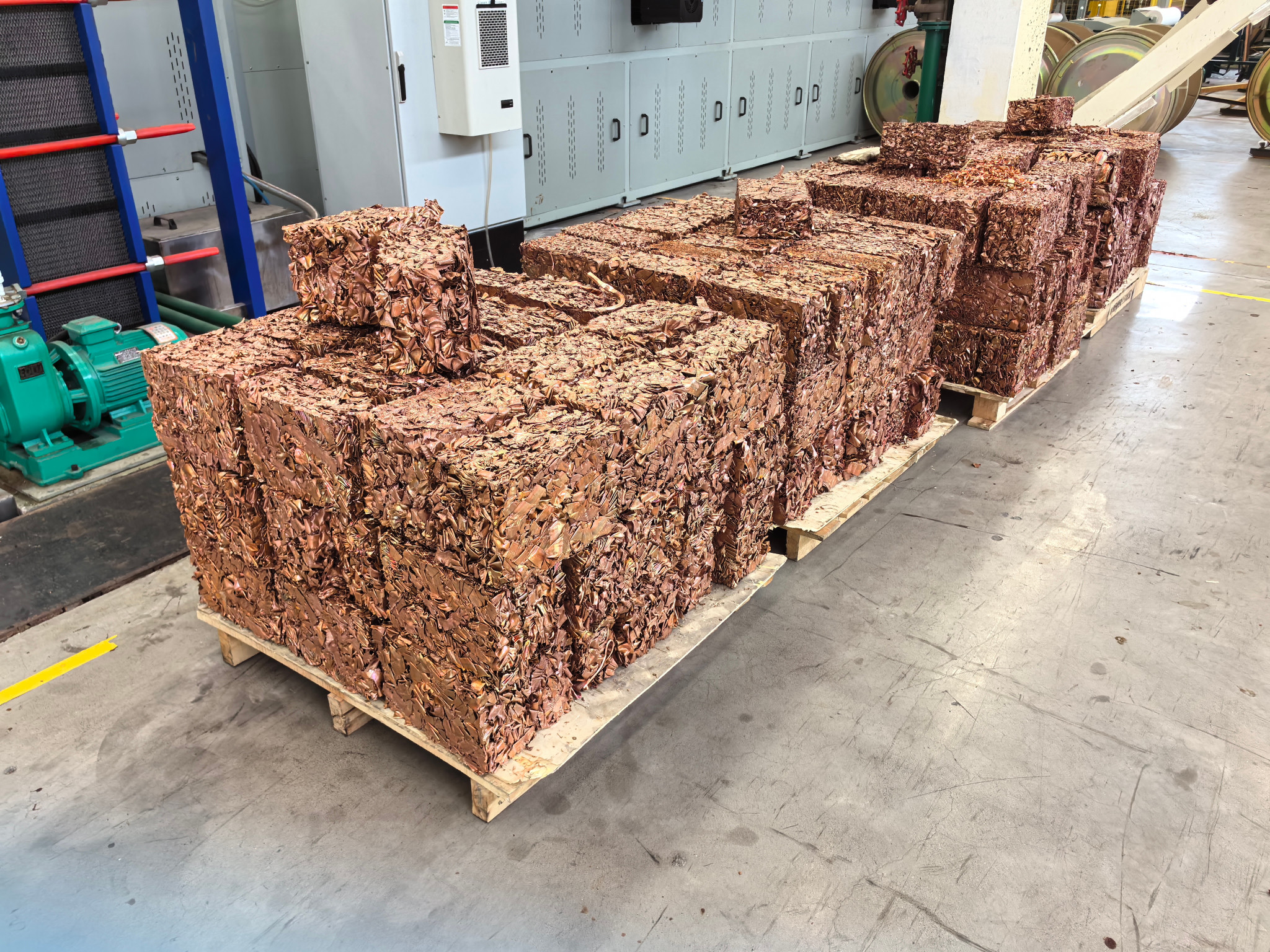 Rectangular copper-colored scrap metal bales stacked on pallets