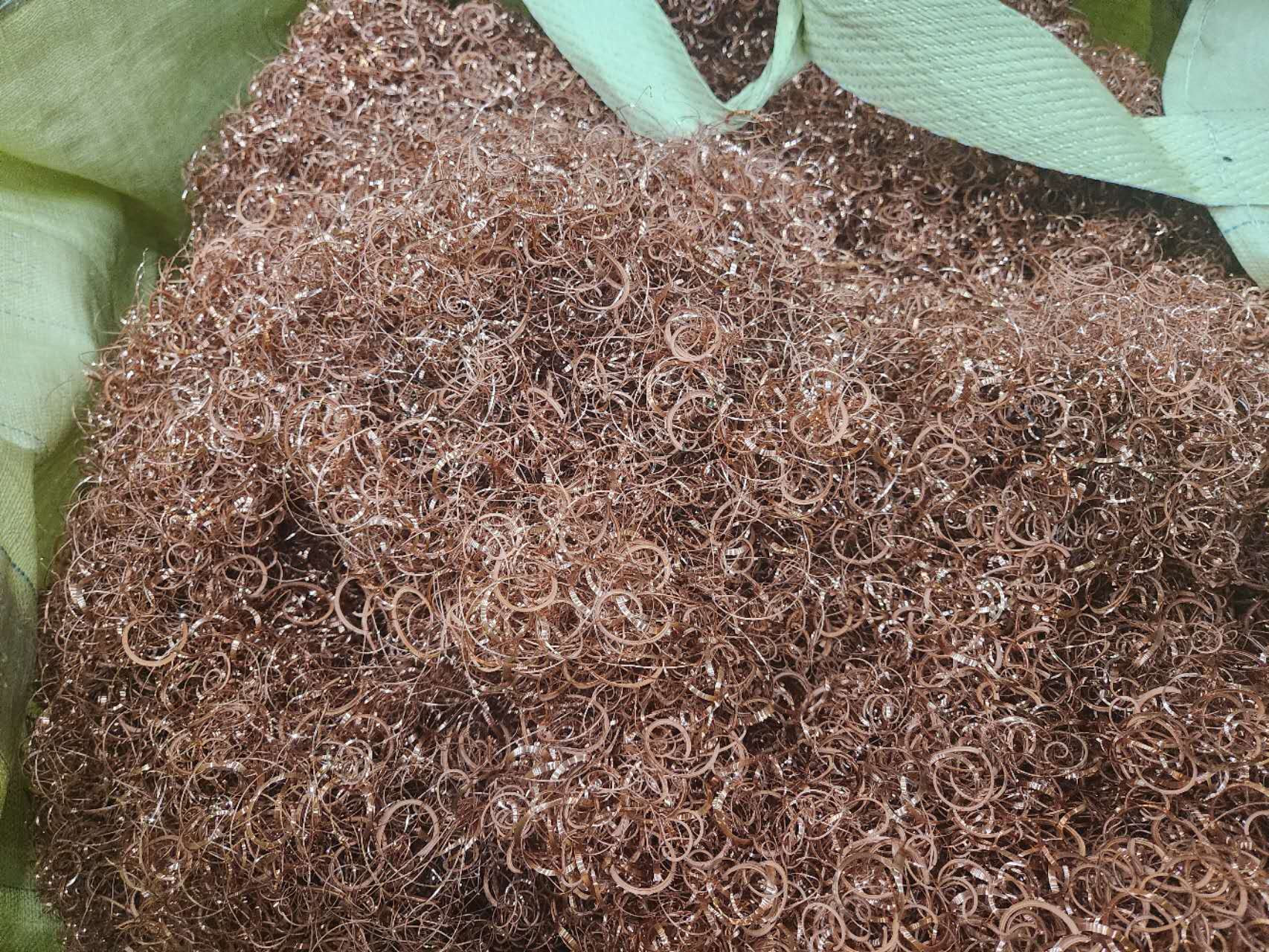 Loose copper-colored metal turnings in collection bags